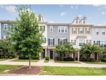 Three-story townhouses with gray and beige siding, landscaping, and a sidewalk at 9714 Ainslie Downs St, Charlotte, NC 28273