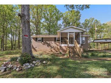 Charming brick home with a screened-in porch, mature trees, and a large front yard at 1725 Feature Rd, Lancaster, SC 29720