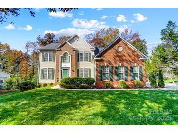 Inviting brick and siding home with lush green lawn, manicured bushes, and colorful fall foliage at 138 Huntly Ln, Mooresville, NC 28115