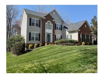 Traditional two-story home featuring a brick facade, lush lawn, and manicured shrubbery at 138 Huntly Ln, Mooresville, NC 28115