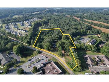 Aerial view showing a property lot with surrounding trees and nearby buildings at 1116 Medlin Rd, Monroe, NC 28112