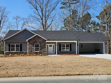 Charming single-story home boasts stone accents and attached two-car garage, complemented by a well-manicured lawn at 2054 Cane Mill Rd, Lancaster, SC 29720