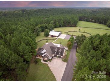 Stunning aerial view of a large country estate with mature trees, fencing, barn and expansive lawn at 1046 Sutton Spring Rd, York, SC 29745