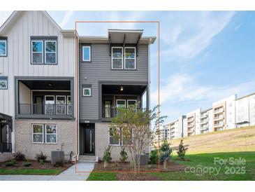 Charming townhome boasts a modern gray exterior with brick accents and a cozy second-story balcony at 440 Nathaniel Way # Brx0041, Charlotte, NC 28213