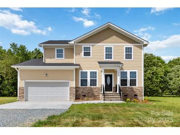 Charming two-story home with stone accents, a well-manicured lawn, and an attached two-car garage at 1034 Heath Helms Rd, Monroe, NC 28110