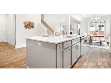 Modern kitchen island with marble countertop, stainless steel sink and faucet, gray cabinets, and adjacent dining area at 332 Shinnville Rd, Mooresville, NC 28115