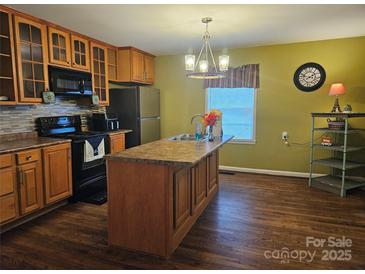 Traditional kitchen boasts wooden cabinets, stainless appliances, island, hardwood floors, and a stylish chandelier at 113 Fairview St, Clover, SC 29710