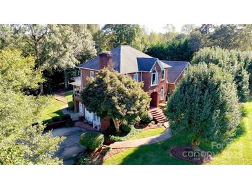 Stunning red brick two-story home with mature trees, lush landscaping, and a welcoming front entrance at 102 Sleaford Ct, Dallas, NC 28034