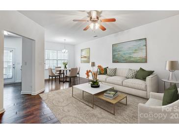 Bright living room features a ceiling fan, neutral paint, and hardwood flooring that flows into the dining area at 9345 Hamel St, Charlotte, NC 28215