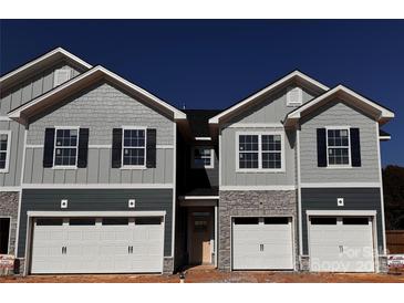 New townhome exterior shows multi-tone gray facade with stone accents, two-car garage, and contrasting black shutters at 4081 Port Richmond Ave # 19, Gastonia, NC 28056