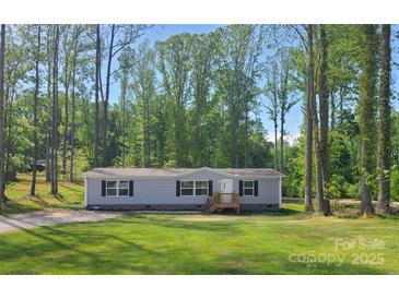 Charming home surrounded by a lush forest, featuring a well-manicured lawn and inviting front porch at 1128 Bethesda Rd, Statesville, NC 28677