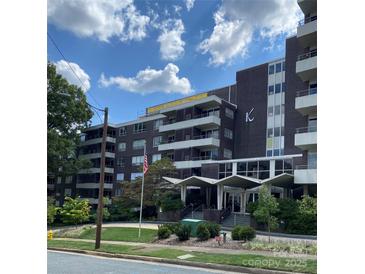 View of the building with manicured front yard and American flag against blue sky at 1300 Reece Rd # 302, Charlotte, NC 28209