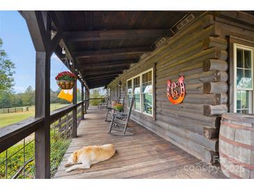 Rustic log cabin porch with rocking chairs, offering a relaxing view at 4796 Dewitt Rd, Blackstock, SC 29014