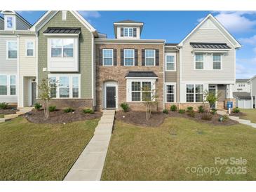 Two-story townhome with brick and siding exterior, landscaping, and walkway at 939 Cobbled Way, Fort Mill, SC 29715