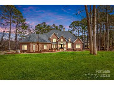 Stunning brick home featuring a well-manicured lawn and lush landscaping, offering timeless elegance and curb appeal at 130 Stonewall Beach Ln, Mooresville, NC 28117