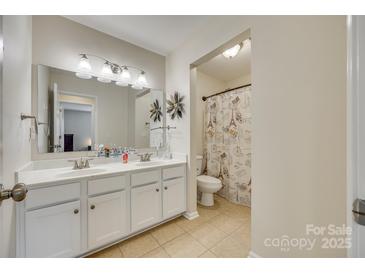 Bright bathroom with a double sink vanity and decorative accents, plus a toilet in a separate alcove at 16840 Rudence Ct, Charlotte, NC 28278