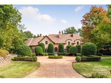 Stone house with circular driveway, manicured landscaping, and a terracotta roof at 4231 Fox Brook Ln, Charlotte, NC 28211