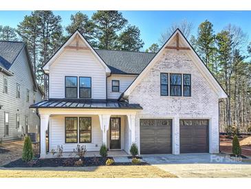 Charming two-story home with a white brick and siding exterior, black trim, and a two-car garage at 2621 Ritz Ln, Matthews, NC 28105