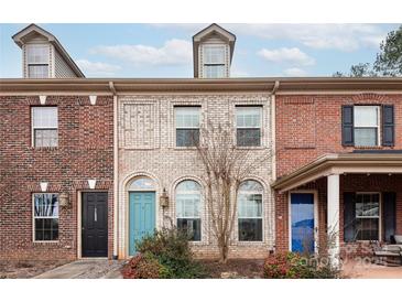 Brick front of charming townhome with teal and blue doors at 11770 Redbridge Blvd, Locust, NC 28097