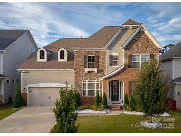 Two story home with brick and stone accents, a three car garage, and landscaping at 13050 Regent Grove Ln, Huntersville, NC 28078