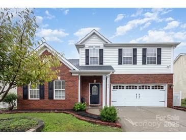 Brick two-story house with a white two-car garage and landscaped front yard at 11434 Lamoille Ln, Charlotte, NC 28278