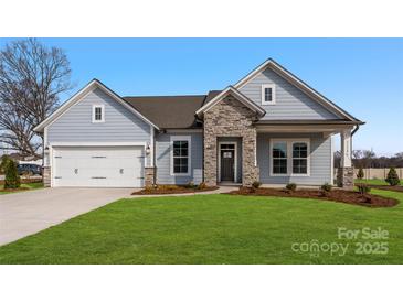 Charming single-story home featuring stone accents, a two-car garage, and a well-manicured lawn at 3228 Gavin Ln, Harrisburg, NC 28075