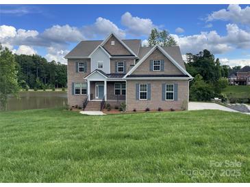 Beautiful two-story brick home with a manicured lawn and lake view at 9411 Stonebridge Way # 49, Mint Hill, NC 28227
