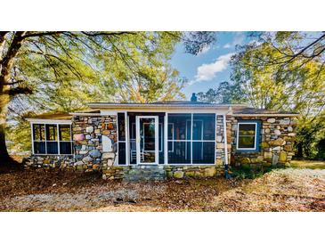 Stone house exterior with screened porch and autumn foliage at 5011 Lewis Rd, Gastonia, NC 28052