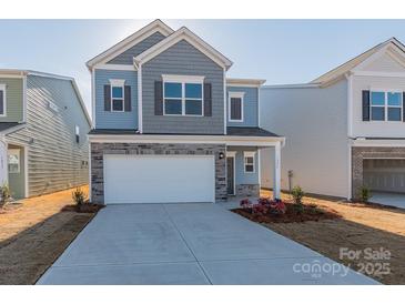 Charming two-story home with a two-car garage, stone accents, and blue siding at 1209 Red River Dr, Salisbury, NC 28144