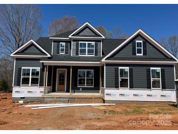 New two-story home featuring dark siding, white trim, symmetrical windows, and a covered front porch at 552 Fern Hill Rd # 21, Mooresville, NC 28117