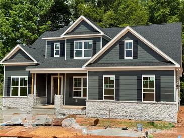 New construction home featuring gray siding, stone accents, black shutters, and a covered front porch at 552 Fern Hill Rd # 21, Mooresville, NC 28117