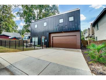 Contemporary two-story home featuring a striking metal facade and a wood-tone garage door at 2107 W Trade St, Charlotte, NC 28216