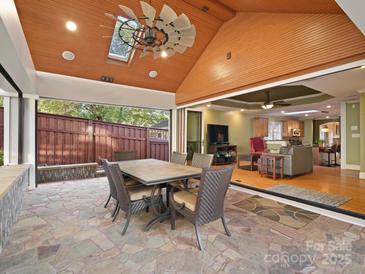 Covered patio with stone flooring, dining table, and views of the backyard at 316 W Kingston Ave, Charlotte, NC 28203