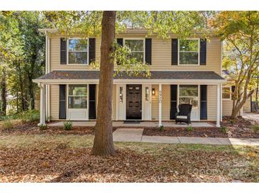 Two-story house with beige siding, black shutters, and a covered porch at 6920 Wyndbend Ln, Mint Hill, NC 28227