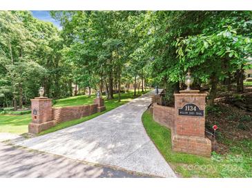 Long driveway leading to home entrance, flanked by brick pillars and lush trees at 1134 Willow Oaks Trl, Matthews, NC 28104