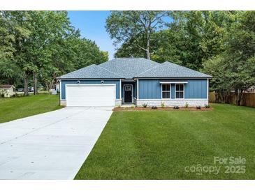 Charming blue one-story home with a manicured lawn, concrete driveway, and a two-car garage at 337 Autumn Dr, Harrisburg, NC 28075