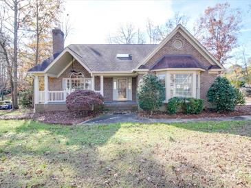 Charming single-story brick home featuring a well-manicured front yard and inviting porch at 909 Woodhurst Dr, Monroe, NC 28110