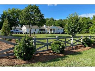 Charming single-story home with a long driveway, beautiful lawn, and decorative wooden fence at 796 Cornelius Rd, Mooresville, NC 28117