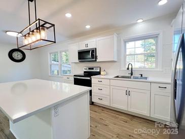 Modern kitchen featuring white cabinets, stainless steel appliances, and a stylish island with a white countertop at 809 23Rd E St, Newton, NC 28658