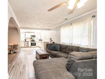 Open living room with L-shaped sectional sofa, view into kitchen, and hardwood floors at 1378 8Th Nw St, Hickory, NC 28601