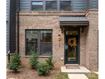 Brick and gray siding townhouse exterior with a front door and landscaping at 412 Tristram Ln, Charlotte, NC 28205