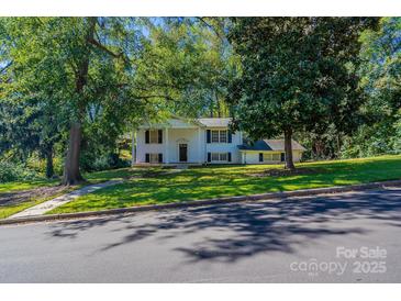 Charming two-story home with white facade and a lush green lawn surrounded by mature trees at 349 Dublin Ct, Gastonia, NC 28054