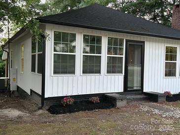Charming house with a new black roof, white siding, and a beautiful touch of pink flowers in the front yard at 7608 Kershaw Camden Hwy, Kershaw, SC 29067