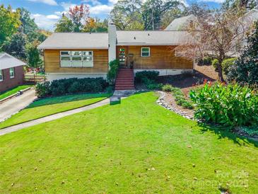 Charming one-story home featuring a well-manicured lawn, wood siding and a traditional brick staircase to the front door at 1166 Montford Dr, Charlotte, NC 28209