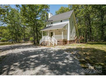Charming white two-story home with a welcoming front porch and a spacious gravel driveway nestled in a wooded lot at 1062 Full Count Ln, Lancaster, SC 29720