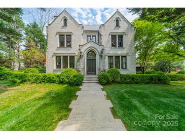 Stunning stone home with manicured lawn, mature trees, and a welcoming walkway leading to the front door at 1919 Kensal Ct, Charlotte, NC 28211