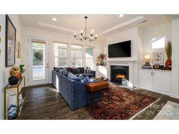 Cozy living room featuring a fireplace, comfortable sectional sofa, and access to a patio at 216 Portrait Way, Indian Trail, NC 28079