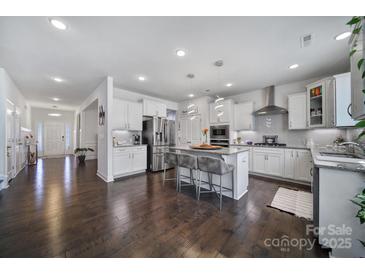 Bright kitchen boasts stainless appliances, granite counters, large island with bar seating and hardwood floors at 535 Red Wolf Ln, Clover, SC 29710