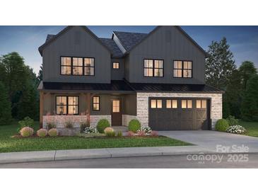 New construction two-story home with a two-car garage, stone accents, and a landscaped front yard at 15009 Brownleigh Ln # 26, Huntersville, NC 28078