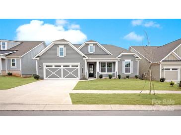 Charming gray home with a two-car garage and beautiful landscaping, set against a bright blue sky at 4440 Moxie Way, Charlotte, NC 28215